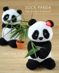 two stuffed panda bears sitting next to each other on a wooden floor with plants in their hands