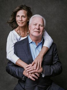 an older man and woman are posing for a portrait with their arms around each other