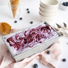 blueberries and ice cream in a pan with spoons on the table next to it