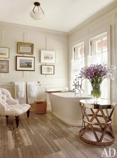 a bath room with a tub a chair and pictures on the wall