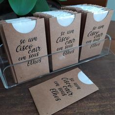 small brown bags with black writing on them sitting on a table next to a potted plant