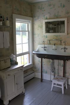 an old fashioned bathroom with a sink and stool next to a window in the corner