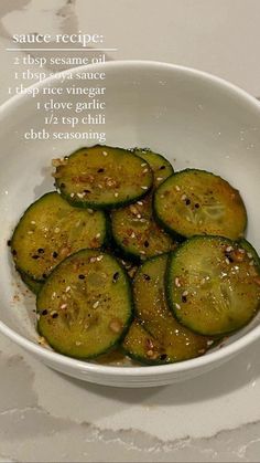 a white bowl filled with sliced cucumbers on top of a marble countertop