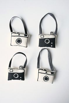 four small cameras are hanging from the straps on this white surface, with one camera attached to it's strap