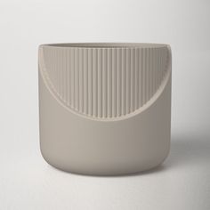 a white vase sitting on top of a table next to a gray cup with a curved lid