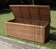 a large wooden box sitting on top of a grass covered park bench next to a sidewalk