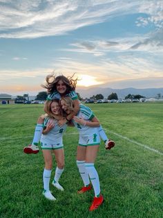 three girls in soccer uniforms are hugging each other on the field with their arms around one another