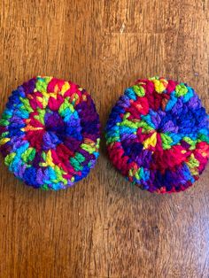 two colorful crocheted objects sitting on top of a wooden table next to each other