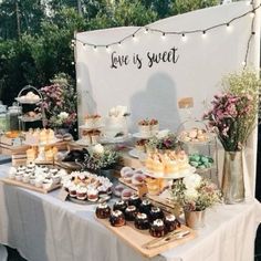 a table topped with cakes and desserts under a white sign that says love is sweet