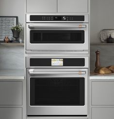 two ovens side by side in a kitchen with gray cabinets and white counter tops