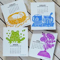 four calendars with different designs on them sitting on a wooden table next to each other