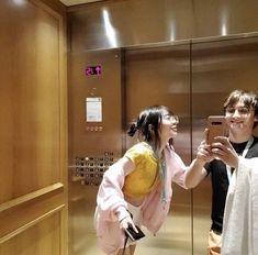 two people taking pictures in an elevator