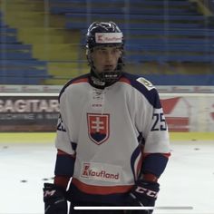 a hockey player standing on the ice with his hands in his pockets and wearing a helmet