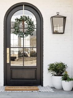 the front door is decorated with wreaths and potted plants, along with two lanterns