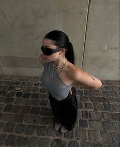 a woman with sunglasses on her face standing in front of a wall