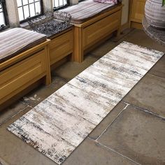 an old rug is laying on the floor next to two beds in a room with windows