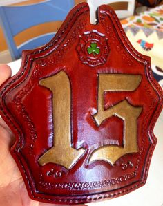 a close up of a person holding a red and gold plaque with the letter f on it