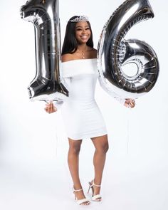 a woman in a white dress is holding some balloons