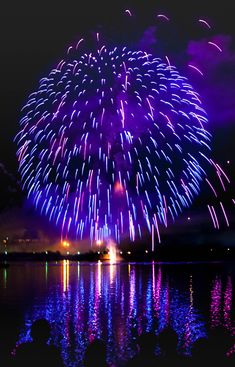 fireworks are lit up in the night sky over water