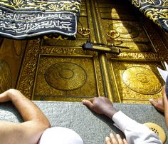 two people laying on the ground in front of an ornate gold door with arabic writing