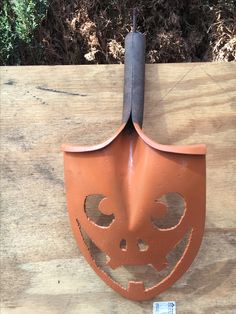 an orange mask hanging on the side of a wooden wall with a black stick sticking out of it