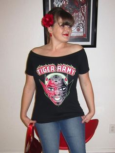 a woman wearing jeans and a t - shirt that says tiger army with a skull on it