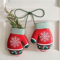 two red mittens hanging on a white door with green and white trimmings