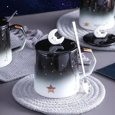 two coffee mugs sitting on top of a white place mat next to each other