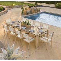 an outdoor dining table next to a swimming pool with chairs and plates on the table