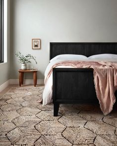 a bed sitting in a bedroom next to a window with a pink blanket on top of it