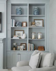 a white couch sitting in front of a book shelf filled with books and vases