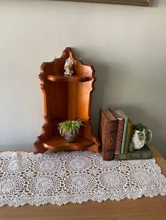 a wooden shelf sitting on top of a table next to two books and a potted plant