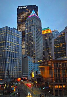 the city skyline is lit up at night, with skyscrapers in the foreground