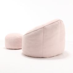 a pink bean bag sitting on top of a white floor next to a round pillow