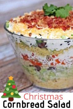 a layered christmas salad in a glass dish on a wooden table with the words, christmas cornbread salad