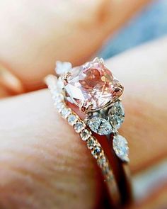 a woman's hand holding an engagement ring with pink and white diamonds on it