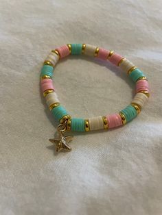 a bracelet with beads and a star charm is on a white cloth covered tablecloth