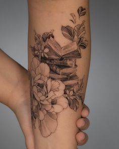 a woman's leg with books and flowers on it