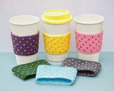 four coffee cups are lined up next to each other with matching knitted napkins