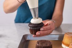 a woman is making cupcakes with icing on top and frosting on the outside