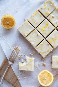 sliced lemon and white chocolate squares on top of parchment paper next to a knife, fork and orange slices