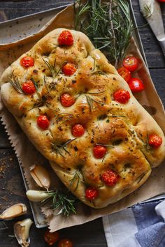 a loaf of bread with tomatoes and herbs on it