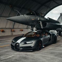 a black and white bugatti parked in front of an airplane