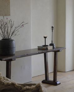 a wooden table with two candles on it next to a potted plant and a candle holder