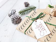 presents wrapped in brown paper and tied with twine on white wooden floor next to pine cones