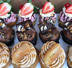 a box filled with lots of different flavored donuts covered in chocolate and strawberries