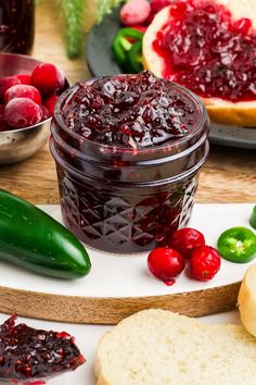 cranberry sauce in a glass jar surrounded by bread, peppers and pickles