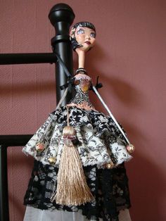 a doll is dressed in black and white with a long skirt, holding two swords