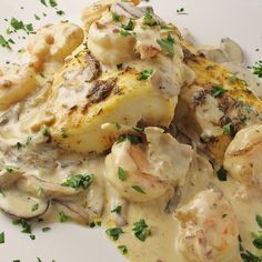 a white plate topped with chicken and mushrooms covered in gravy, garnished with parsley