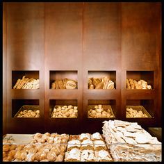 there are many different types of food in the display case on the wall, including breads and pastries